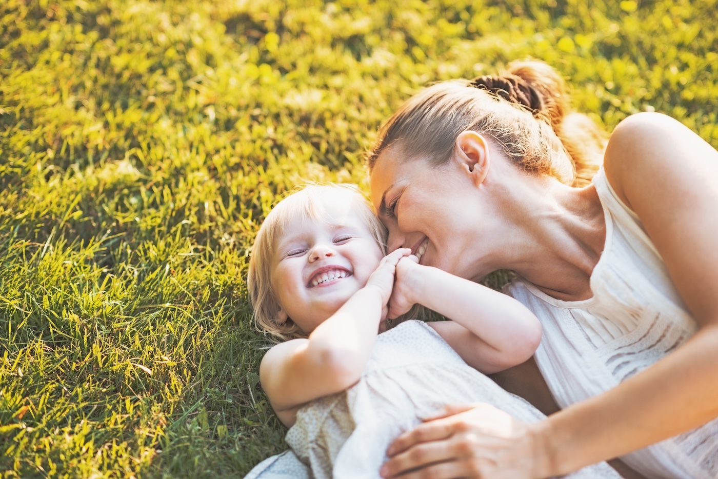 Happy mother and baby laying on meadow